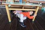 示範地震來了，躲在桌子下保護頭部